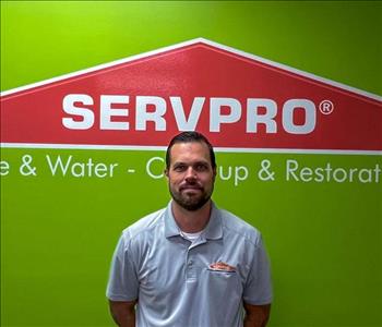 Man standing in front of green wall with SERVPRO logo on it.